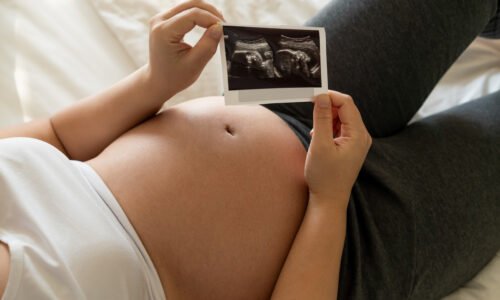 test de grossesse -PMA, première échographie, échographie grossesse, bébé, fertilité, infertilité, grossesse naturelle, projet bébé, début de grossesse, premier trimestre de grossesse, woman feeling happy at home while taking care of her child. The young expecting mother holding baby in pregnant belly. Maternity prenatal care and woman pregnancy concept.
